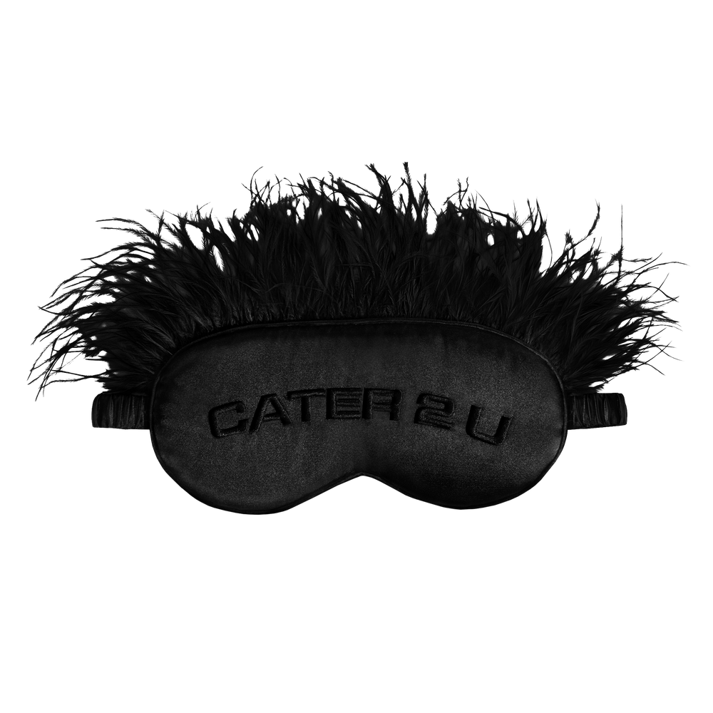 Beyoncé Cater 2 U black feather sleep mask front view featuring embroidered Cater 2 U lettering with glamorous feathered trim and satin texture