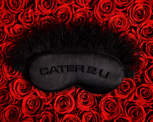 Beyoncé Cater 2 U black feather sleep mask displayed on red rose background featuring romantic luxury aesthetic and embroidered satin design